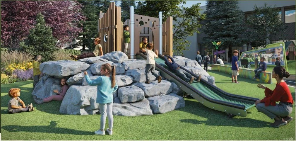 Children climbing and exploring the Boulder Hill natural play feature with rocks and slide in an inclusive playground