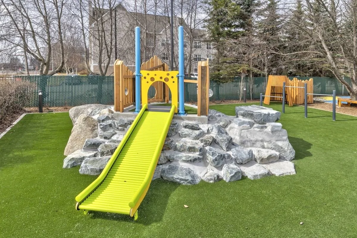 Inclusive playground boulder hill with accessible slide and climbing features for children